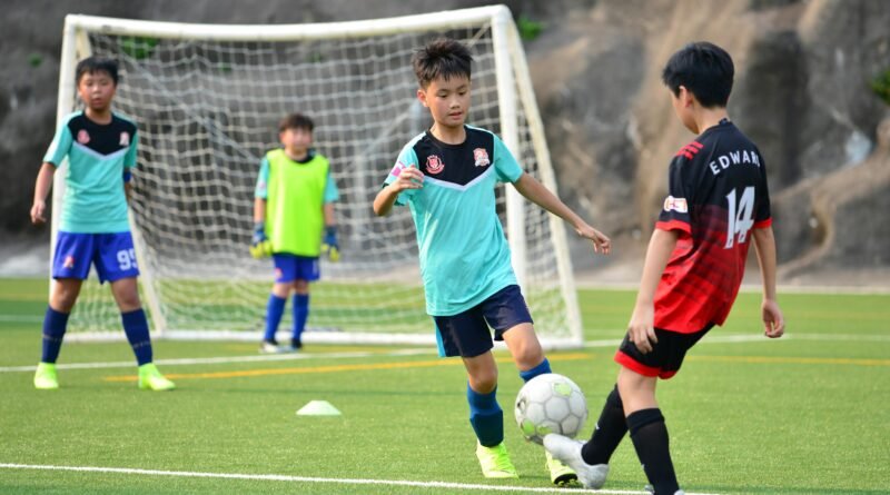 Boys playing soccer during a team training session outdoors on a sunny day.